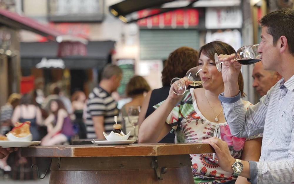 Una pareja tomando un pincho y vino